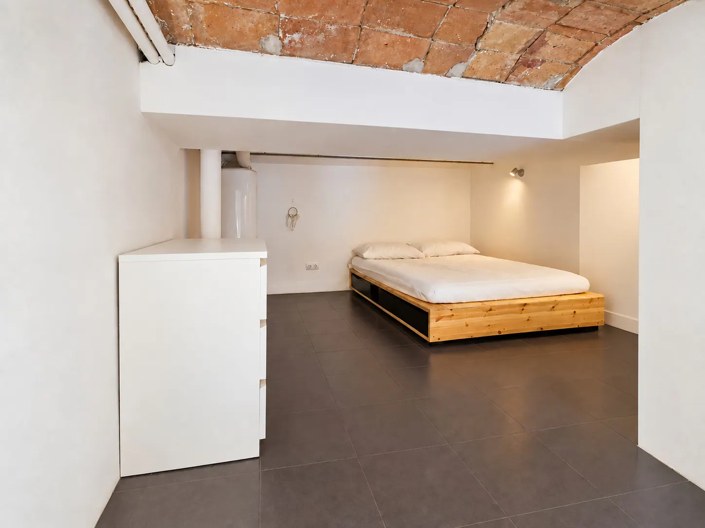 FoL Apartment 01 bedroom with wooden platform bed under a vaulted brick ceiling