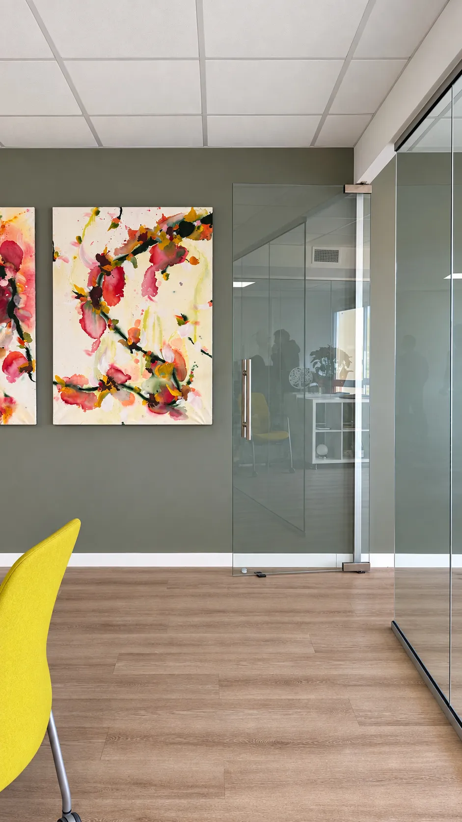 GlG frameless glass door leading to the meeting room beside the floral artwork
