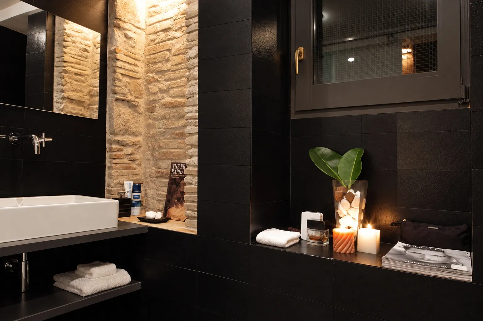 OLi bathroom with black tile walls and brick niche
