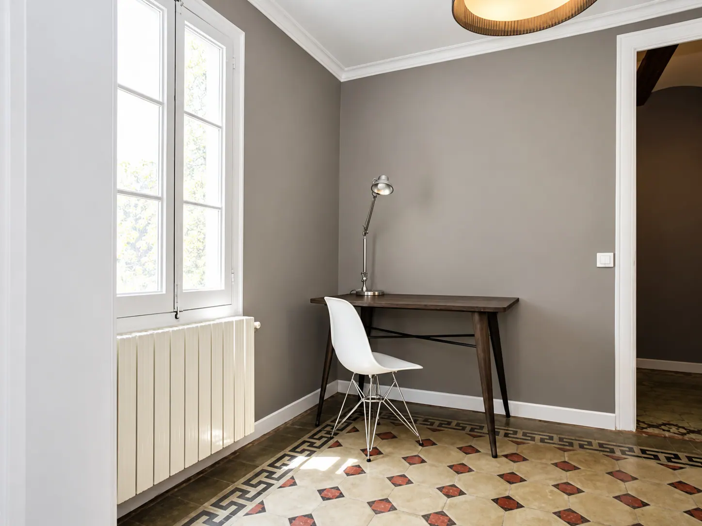 LLn study corner with wooden desk, white chair and floor-length window over tiled floor