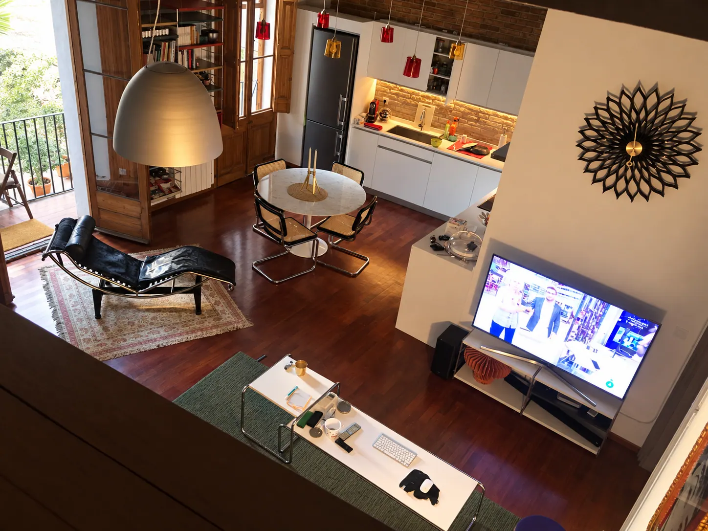 TrF overhead view of the open living area, dining table and kitchen under exposed brick and beams