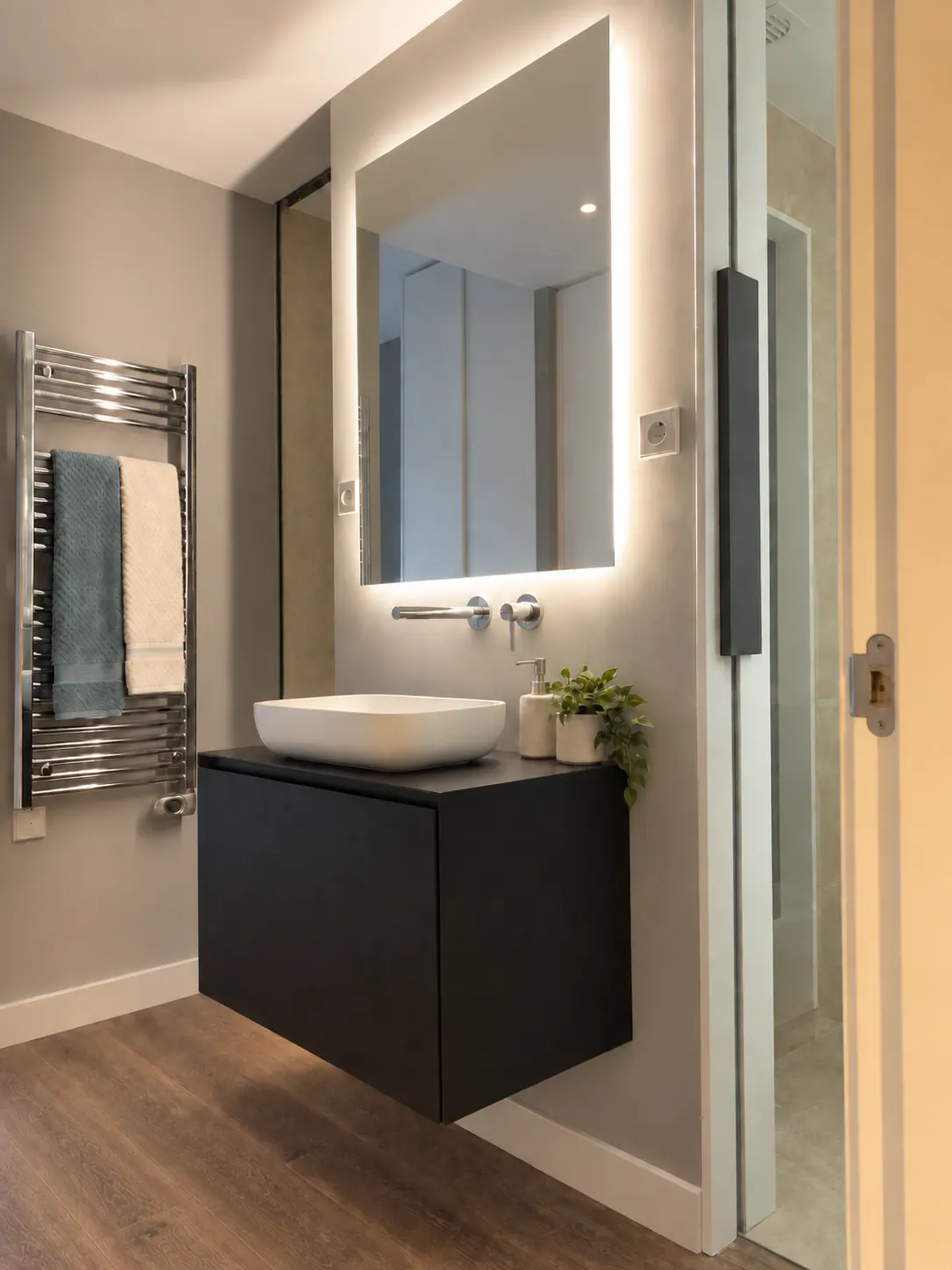 BiG bathroom with matt black floating vanity, backlit square mirror and chrome towel warmer