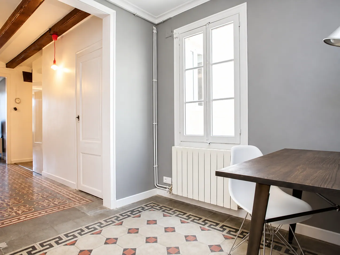 LLn dining area with grey wall, tall window and patterned hydraulic tile floor