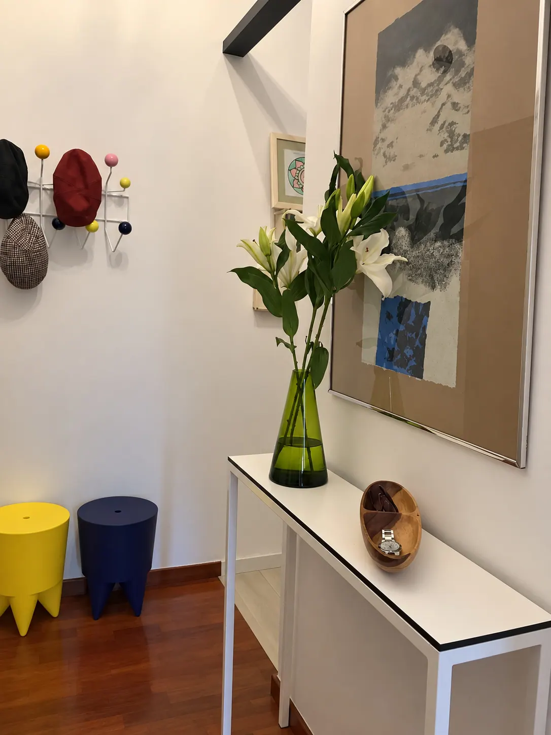 TrF hallway console with green glass vase, artwork and colourful stools and coat rack