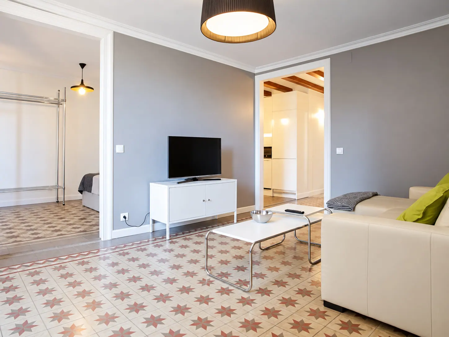 LLn living room with white media cabinet and television, view through to the bedroom and kitchen