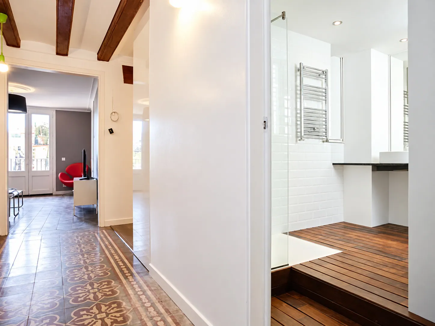 LLn hallway with patterned tiles leading to the living room, bathroom with timber platform behind glass