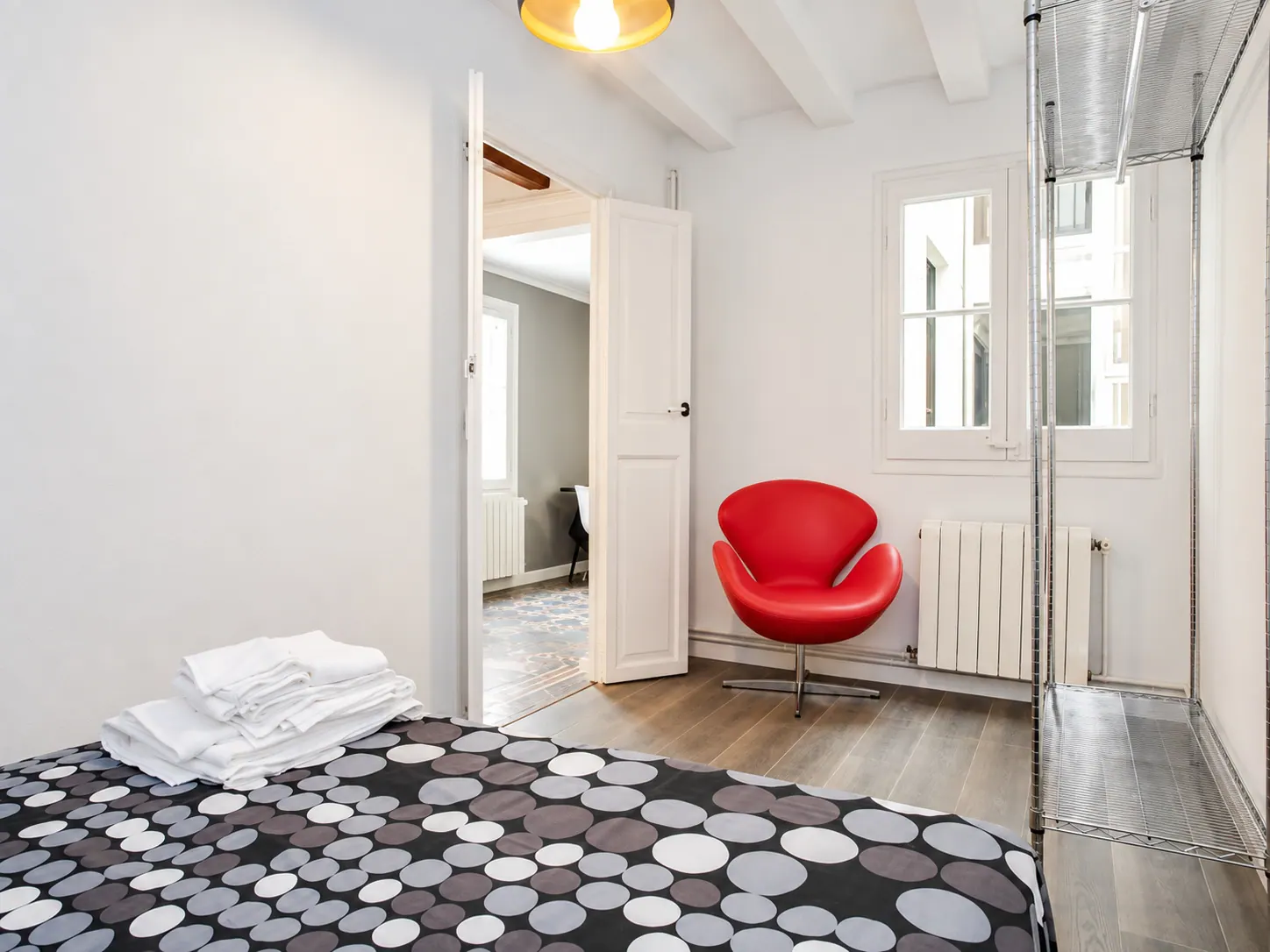 LLn second bedroom with red armchair, metal shelving and white ceiling beams
