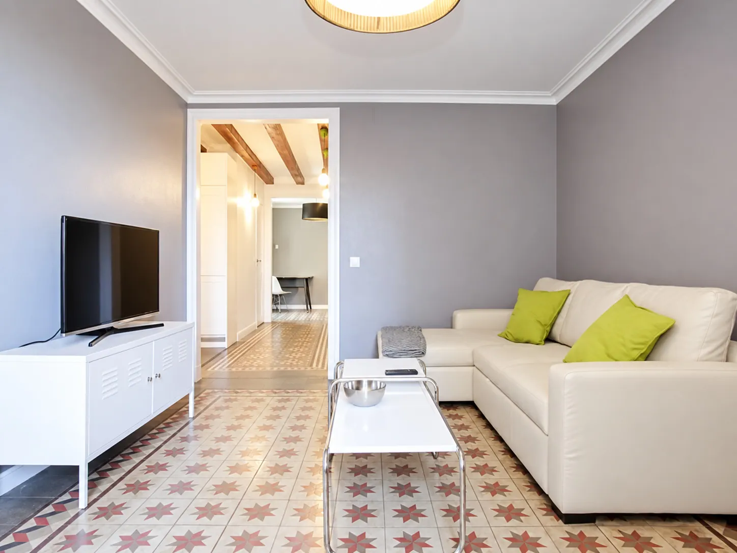 LLn living room with white sofa, green cushions and star-patterned hydraulic tile floor