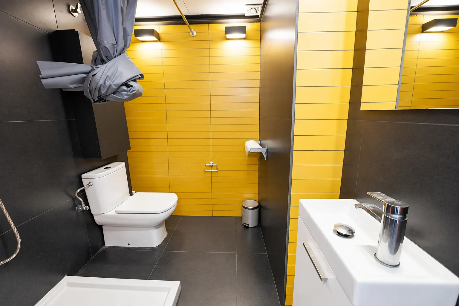 FoL Apartment 02 bathroom with yellow accent wall, white vanity, and dark grey tiling