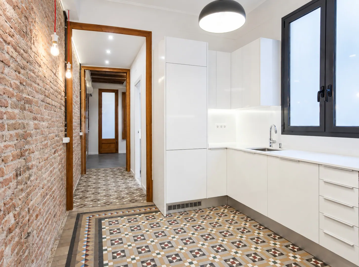 AvN white kitchen with black dome pendant beside a brick corridor with patterned tiles